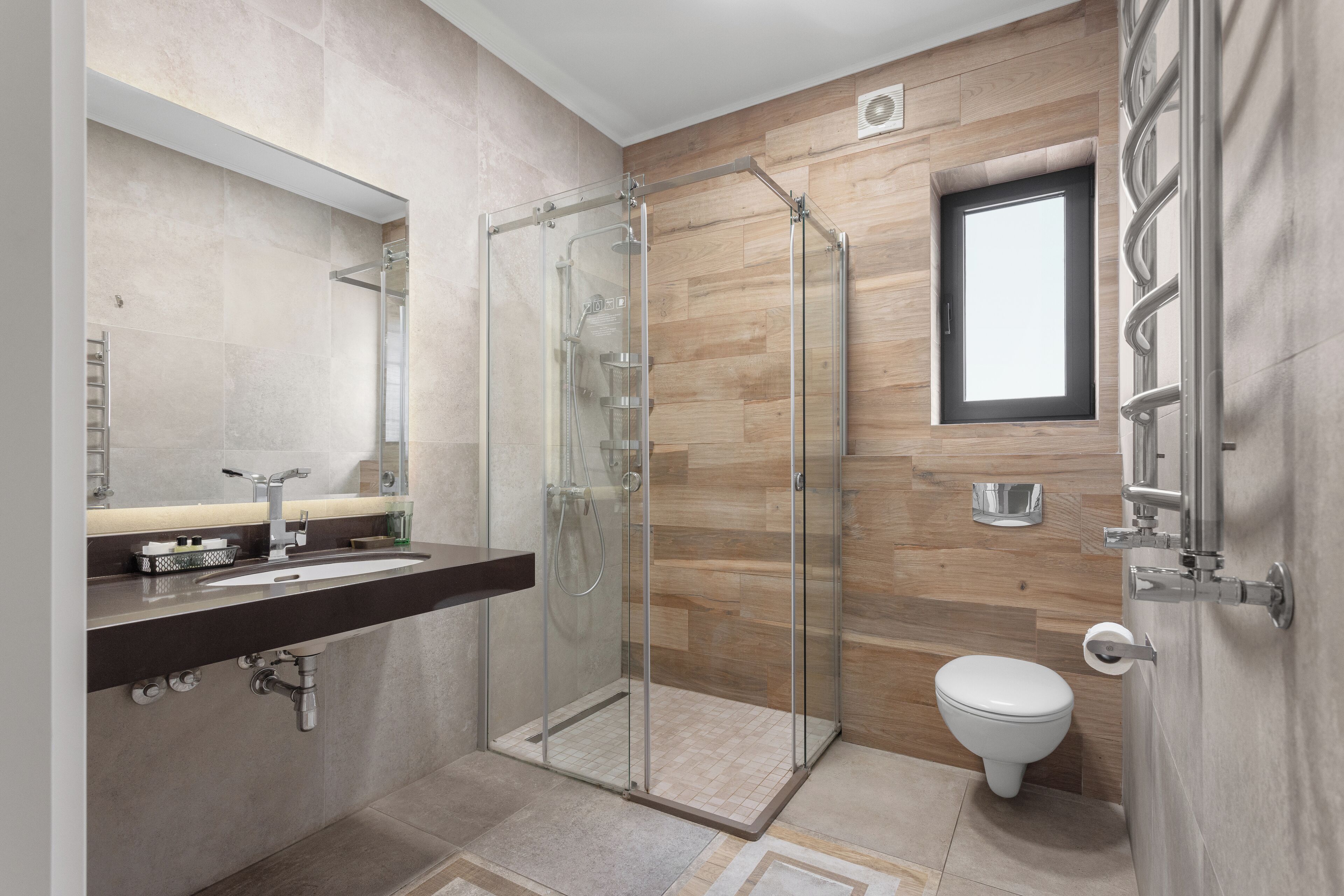 A modern bathroom with a glass shower enclosure, a toilet, and a vanity with a mirror.