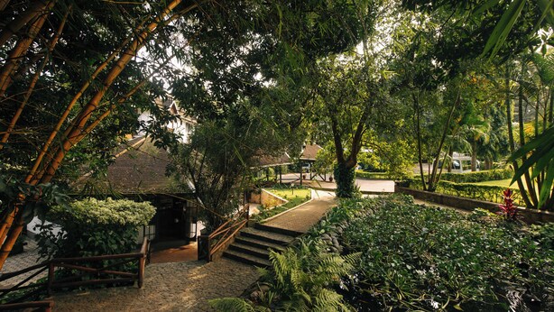 A traditional Japanese-style building with a tiled roof, surrounded by lush greenery and a small pond. - Aishi Machame Hotel (Moshi)