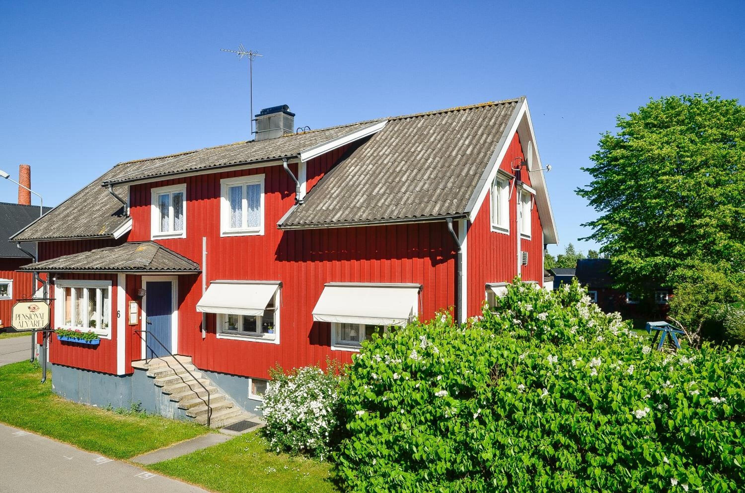 Un bâtiment rouge à deux étages, doté d’un toit en pente, d’un petit porche et d’un escalier menant à l’entrée.