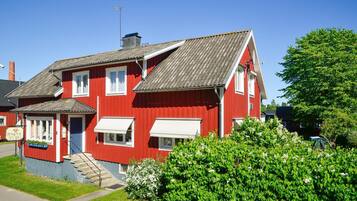 Un bâtiment rouge à deux étages, doté d’un toit en pente, d’un petit porche et d’un escalier menant à l’entrée.