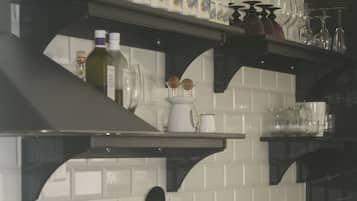 A kitchen with white subway tiles, dark wooden cabinets, and black shelves holding kitchenware.