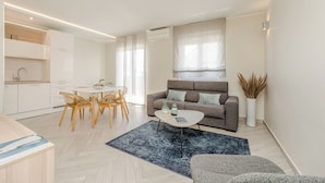 A modern living room with a sofa, coffee table, and dining area. - Apartments Villa Karla (Zadar)