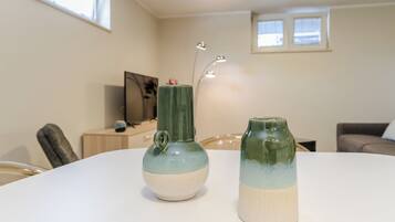 Zwei Keramikvasen auf einem weißen Tisch in einem Raum mit Fernseher, Lampe und Fenster.