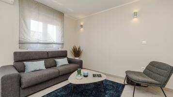 A modern living room with a grey sofa, a matching armchair, a coffee table, and a patterned rug.