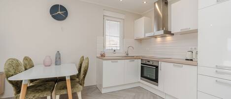 A modern kitchen with white cabinets, a built-in oven, and a herringbone-patterned floor.