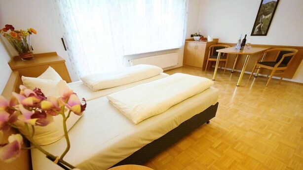 A bedroom with a bed, bedside table, and a desk with a chair. - Boardinghouse Hähn (Koblenz)
