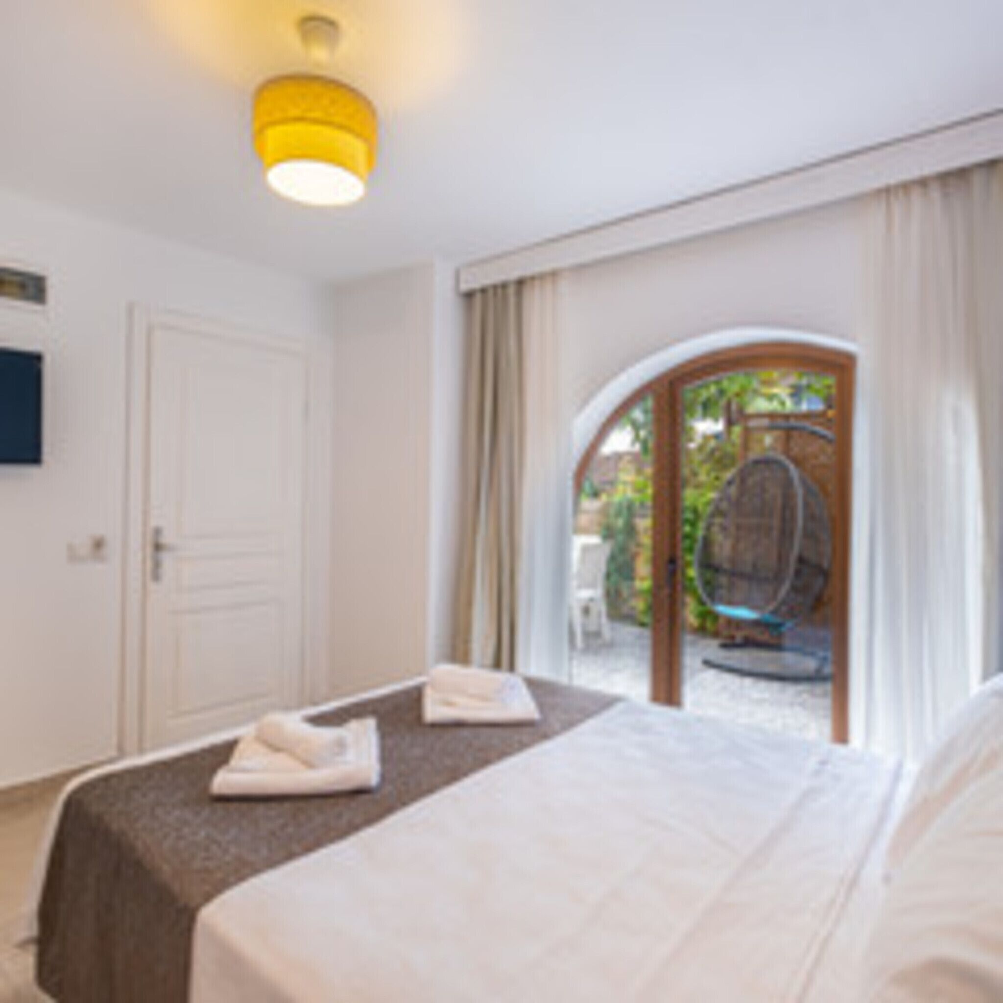 Habitación de hotel con cama, una mesita, una silla y vistas al exterior.
