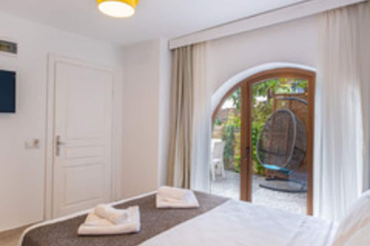 Une chambre d’hôtel avec un lit, une petite table, une chaise et une vue sur l’extérieur.