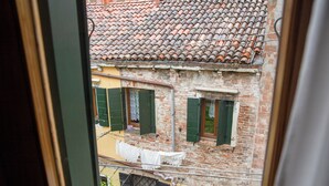 A view through a window of a brick building with green shutters and a tiled roof. - Ca' Marina (Venice)