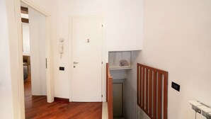 A hallway with wooden flooring, a white door, and a staircase with a wooden railing. - Ca' Marina (Venice)