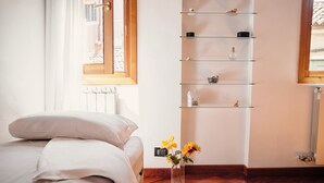 A bedroom with a bed, a vase with flowers, and a wall-mounted shelf with various items. - Ca' Marina (Venice)