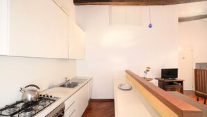 A compact kitchen with a gas stove, sink, and wooden ceiling beams. - Ca' Marina (Venice)