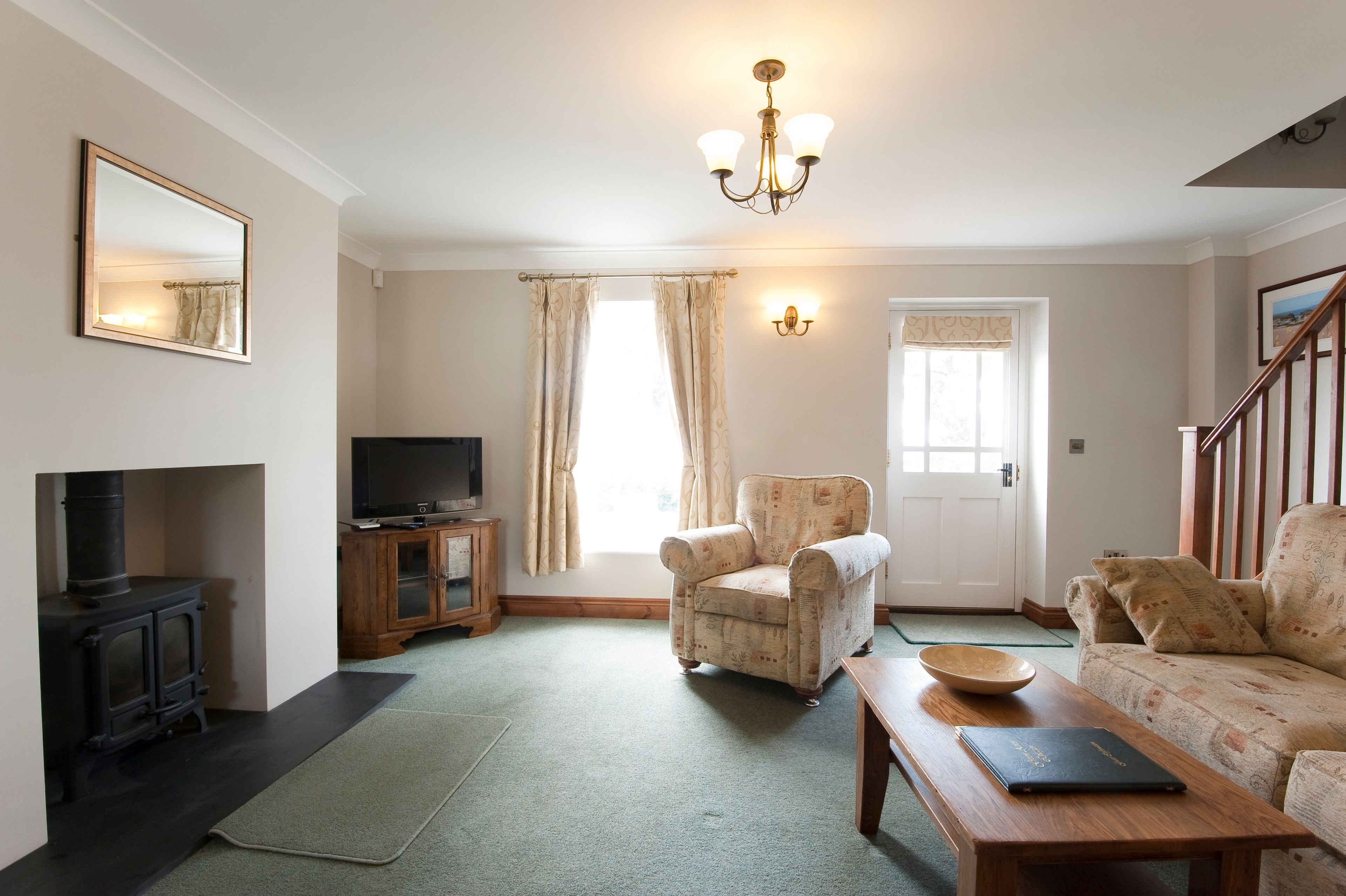 A living room with a fireplace, a sofa, a chair, a wooden table, and a television.