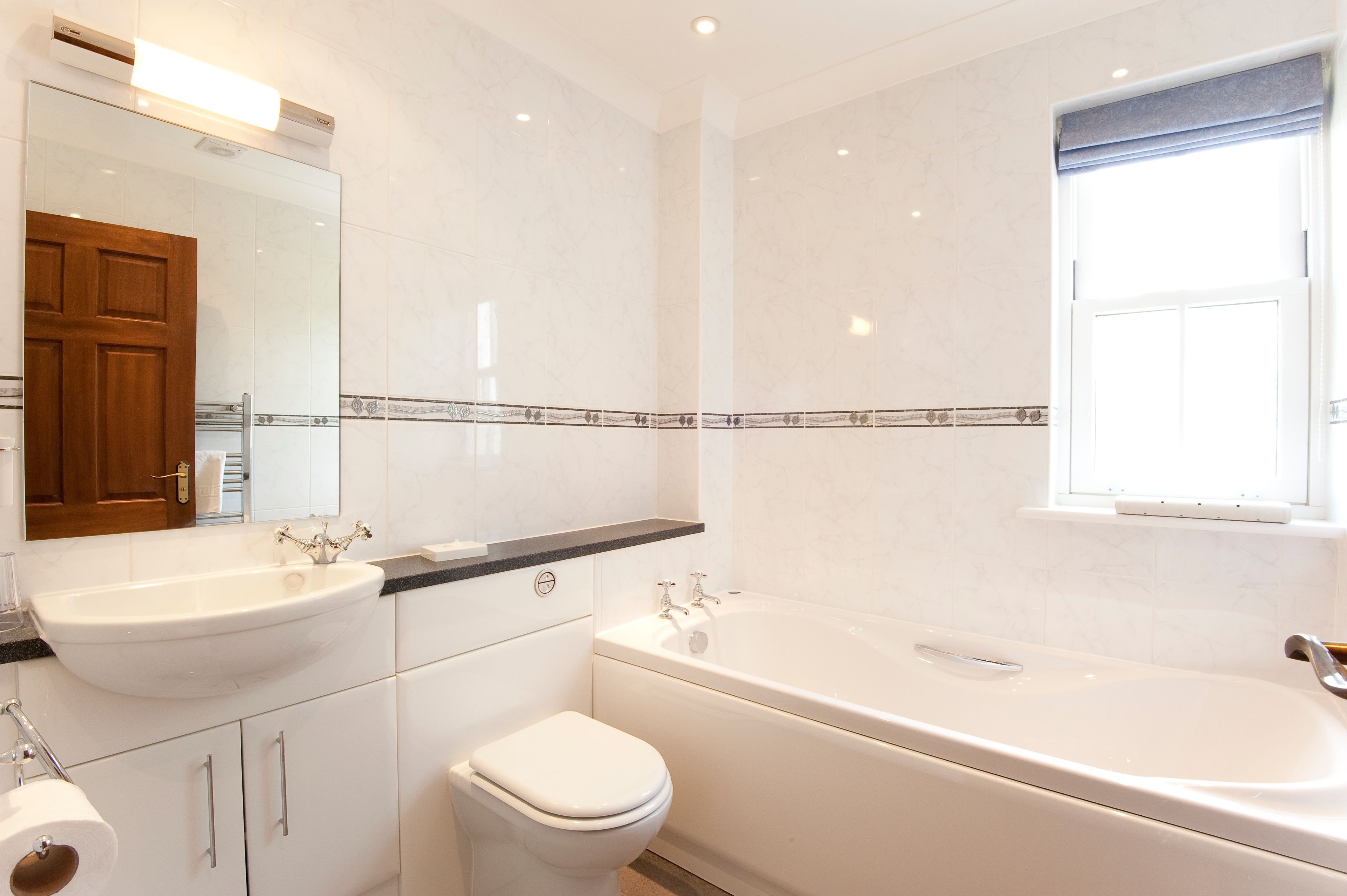 A modern bathroom with a sink, toilet, and bathtub.