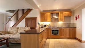 A kitchen with wooden cabinets, a built-in oven, and a countertop. - Green Acres Cottages (Par)