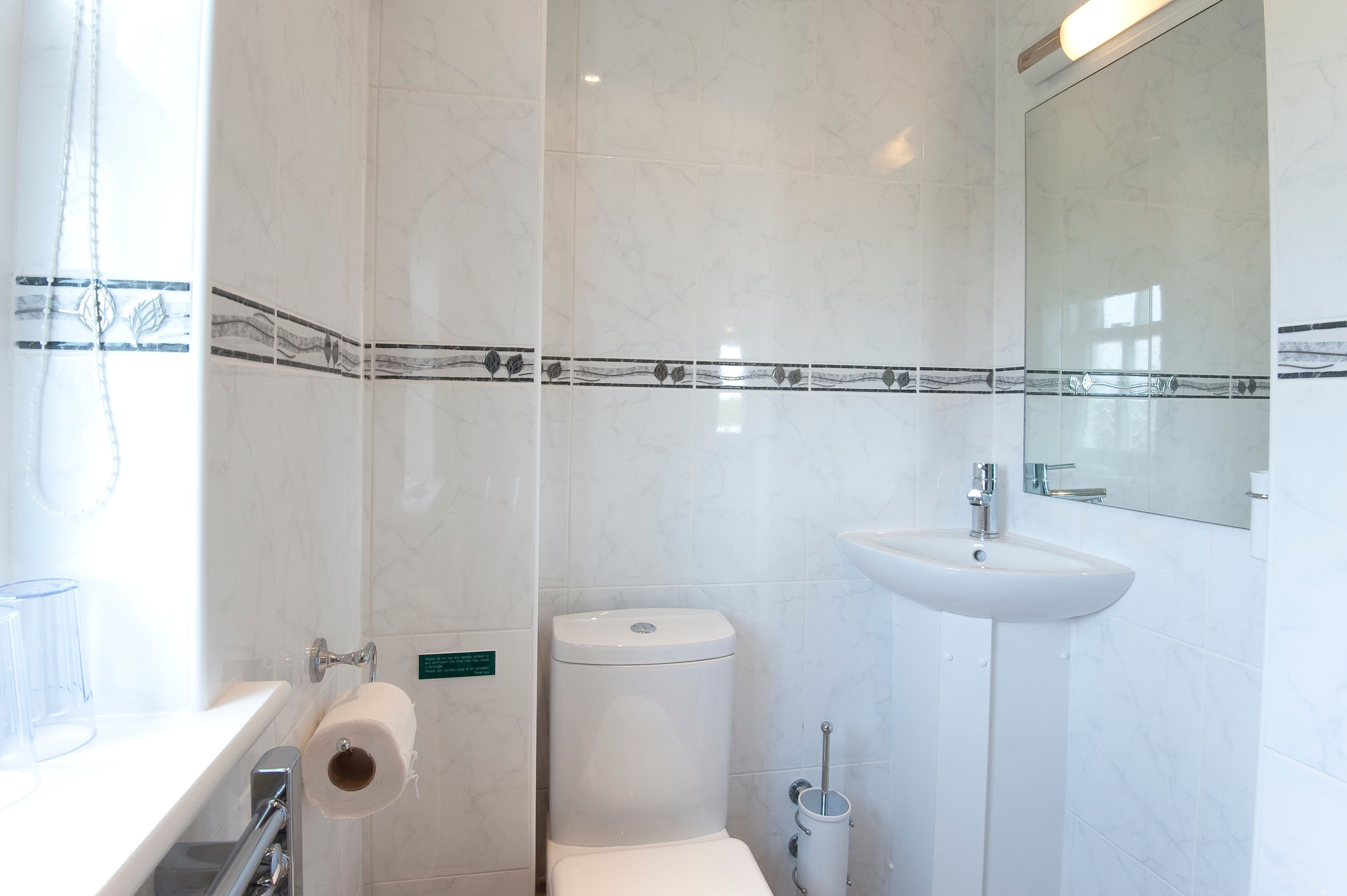 A bathroom with a toilet, sink, and a mirror.