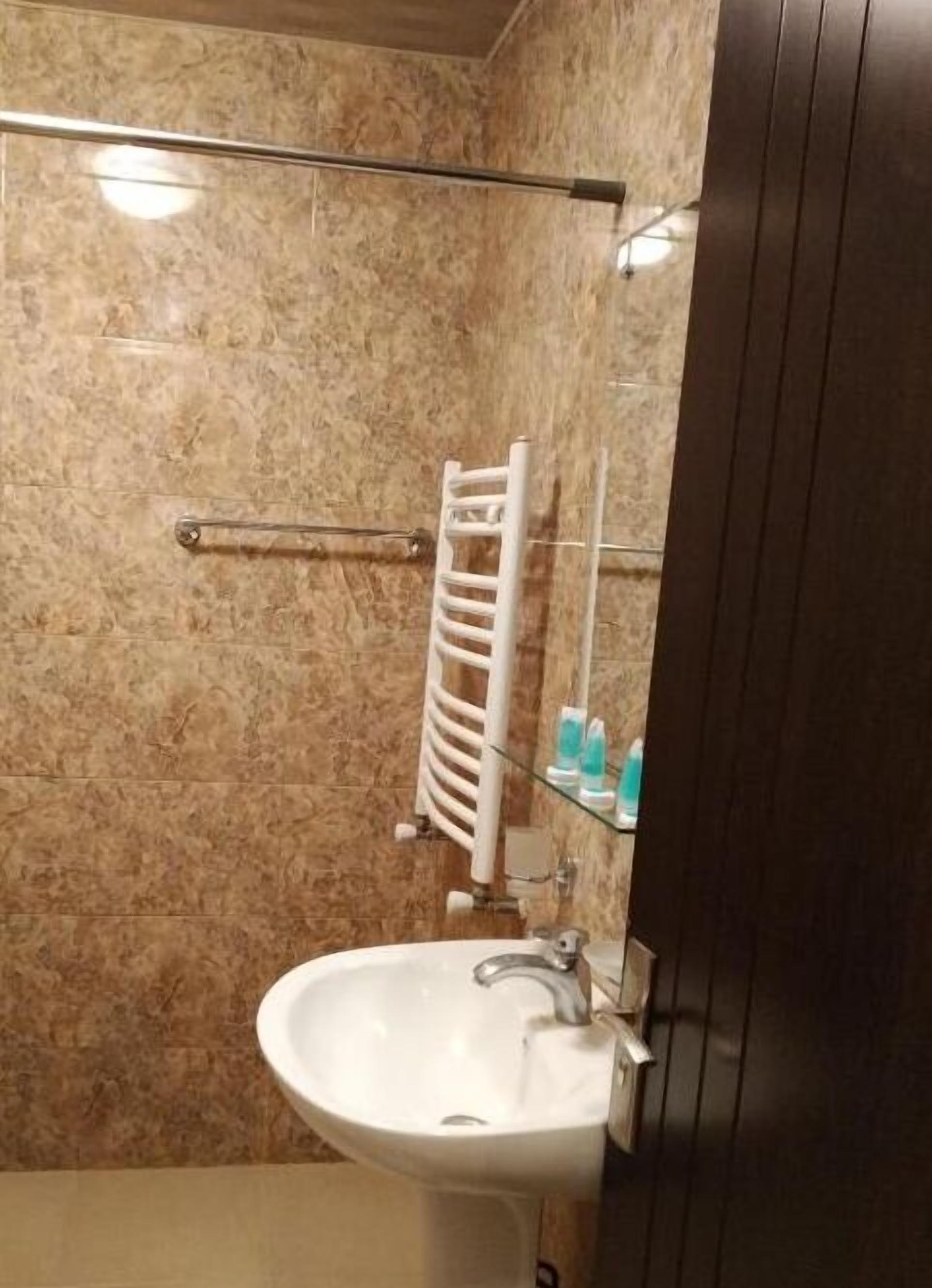 A bathroom with a white sink, a glass shower enclosure, and a towel rack.