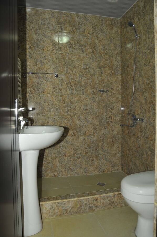 Un baño con pared de mármol, un lavamanos y un inodoro.