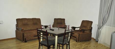 A dining area with a wooden table and six chairs, a sofa, and a TV.