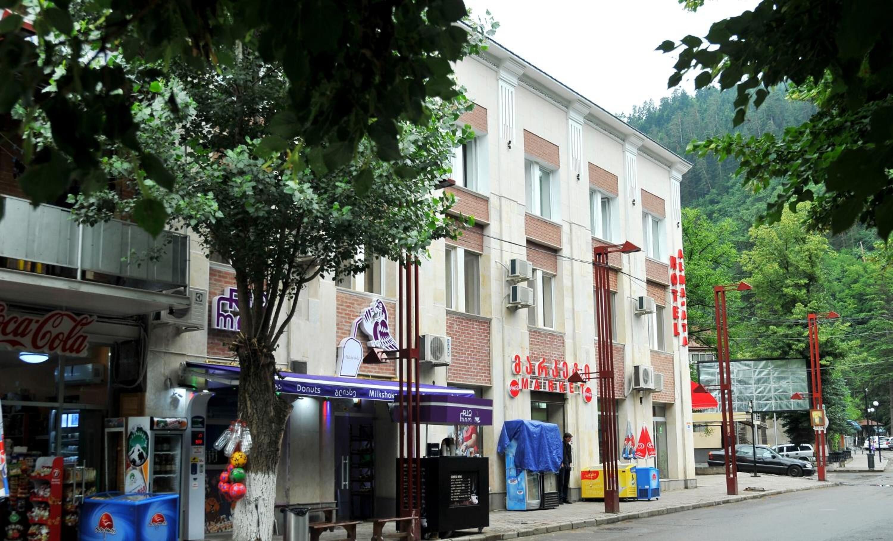 Vista de la calle con un edificio que tiene una heladería, un puesto de Coca-Cola y una panadería.