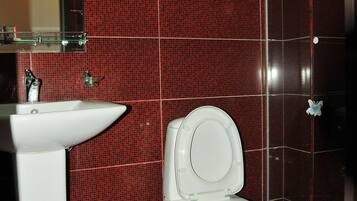 Un baño con paredes de azulejos rojos, un lavamanos blanco y un inodoro.