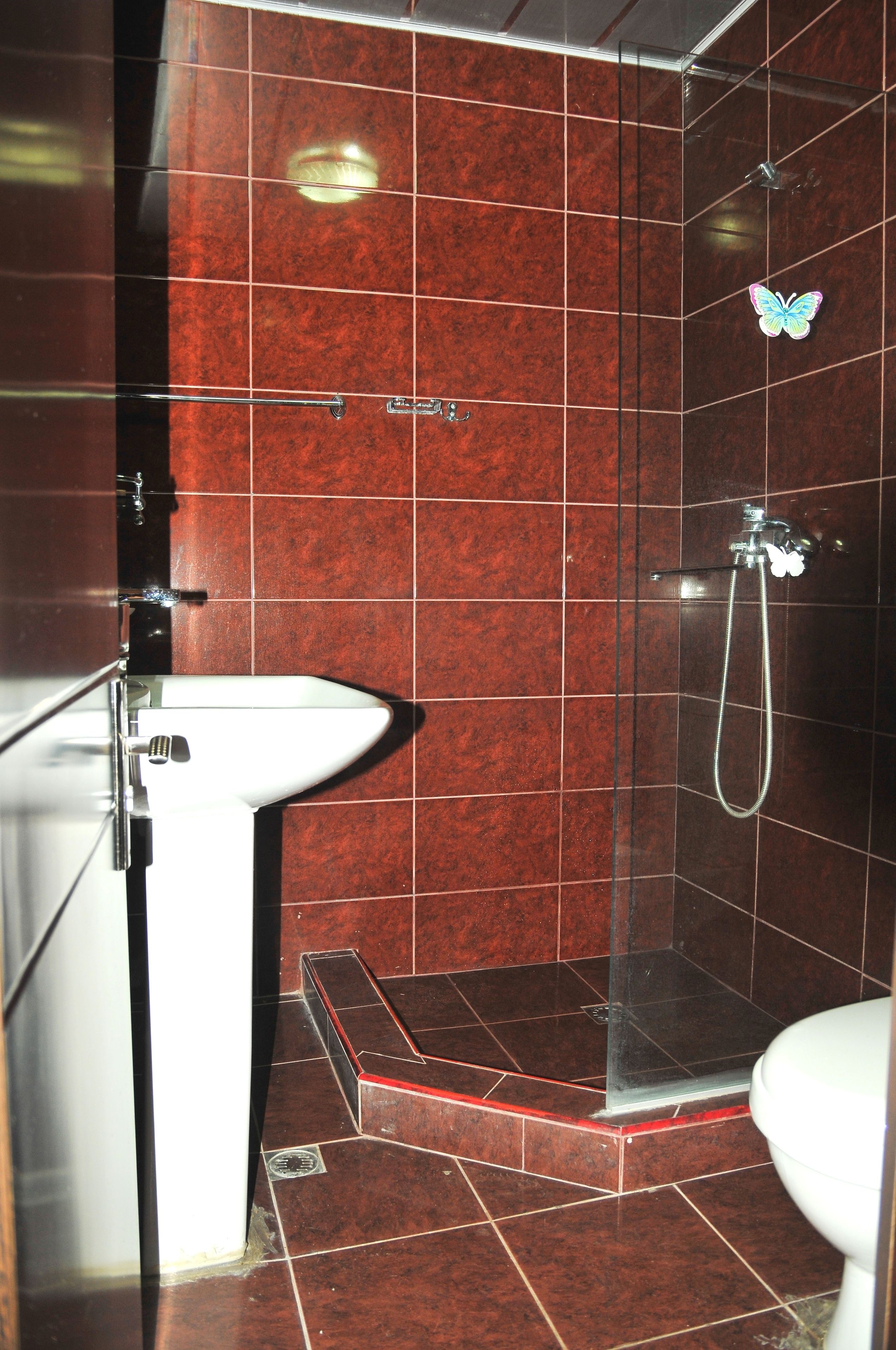 Un baño con lavamanos, ducha y paredes de azulejos.