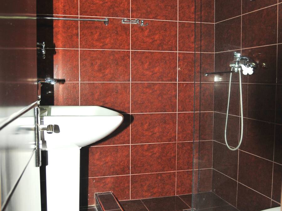 Un baño con lavamanos, ducha y paredes de azulejos.