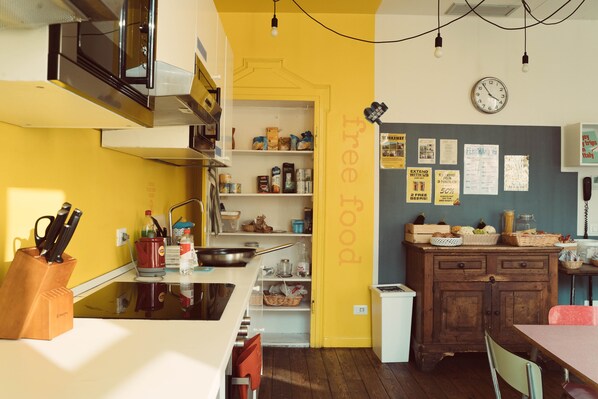 A kitchen with yellow walls, wooden cabinets, and a white countertop. There are various kitchen items and utensils on the counter. - Ostello Bello Lake Como (Como)