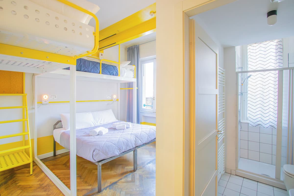A bunk bed with a white mattress and pillows, a yellow ladder, and a window with curtains.