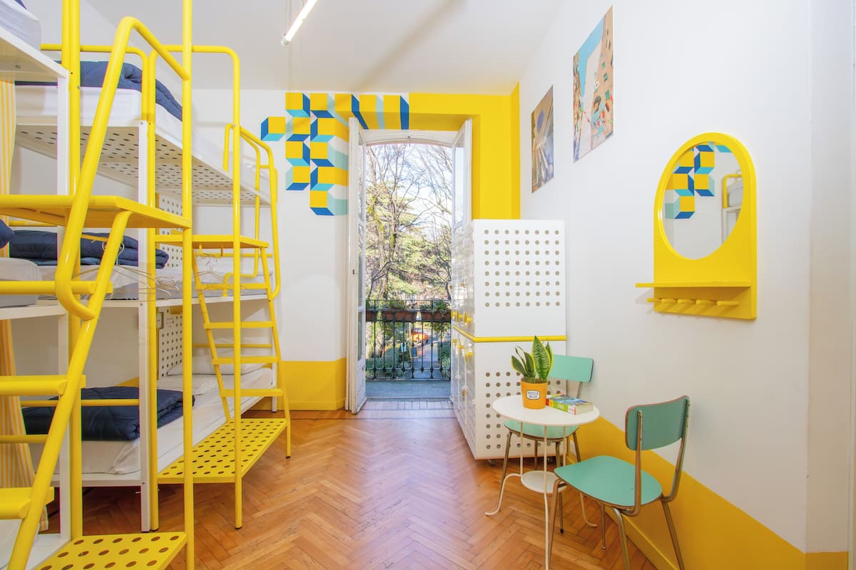 A room with bunk beds, a small table with a chair, and a potted plant.