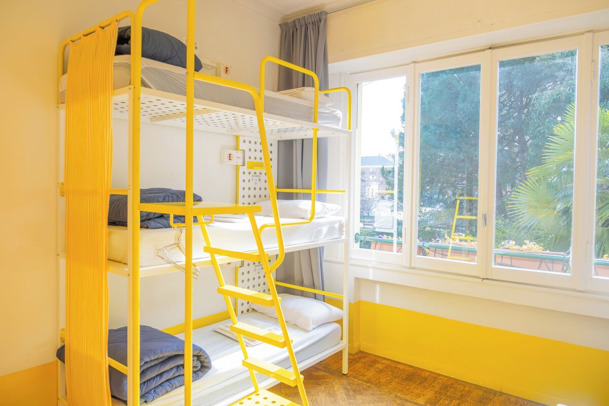 A bunk bed room with a window view, a ladder, and a control panel.