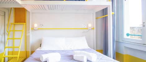A bunk bed room with a ladder, a bed with white pillows, and a window with curtains.
