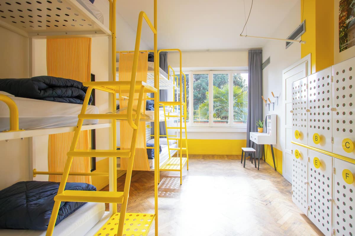 A bunk bed room with a window, a desk, and a storage unit with labeled compartments.