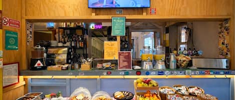 A breakfast buffet area with a variety of food items and a coffee station.