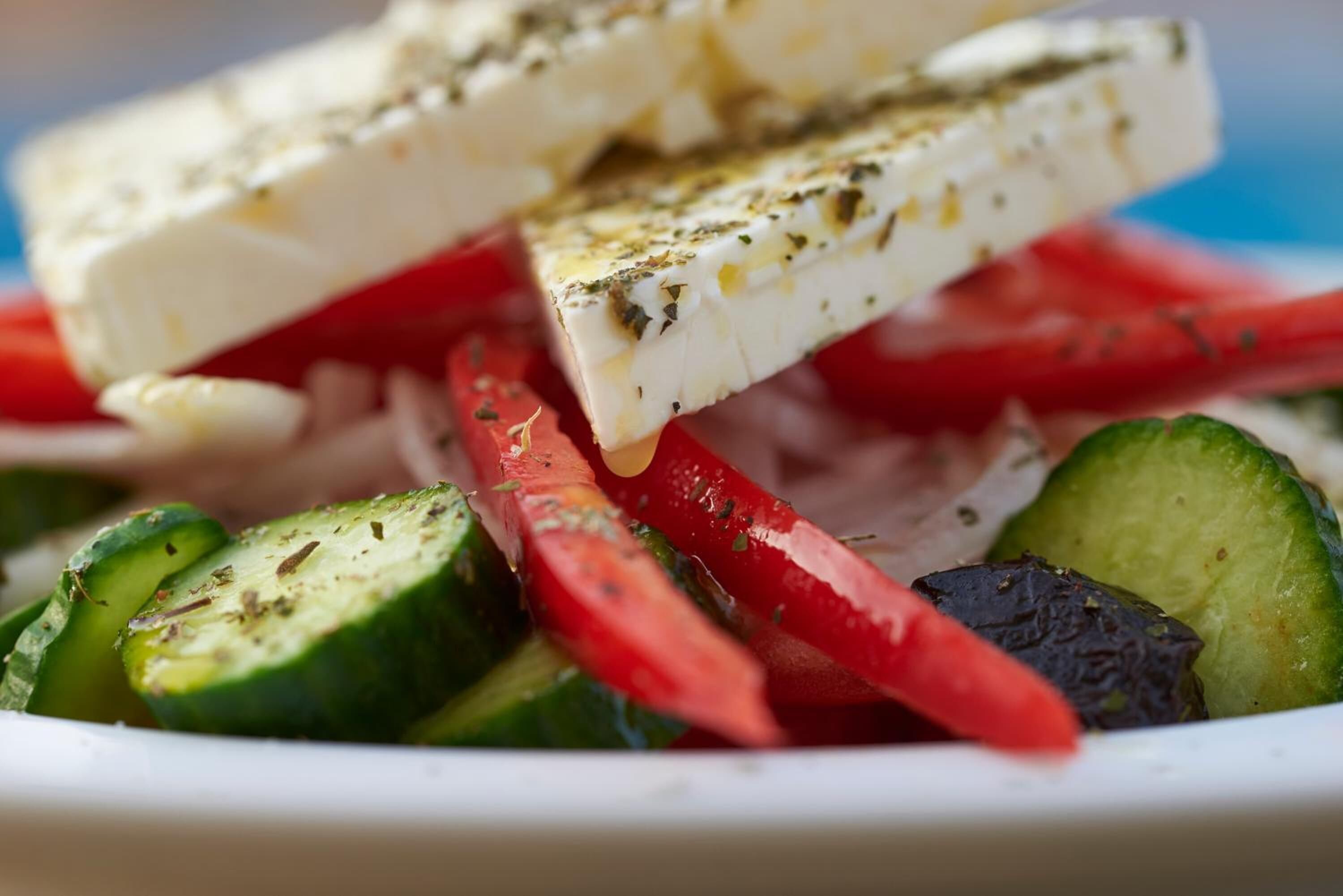 A plate of feta cheese and sliced vegetables.