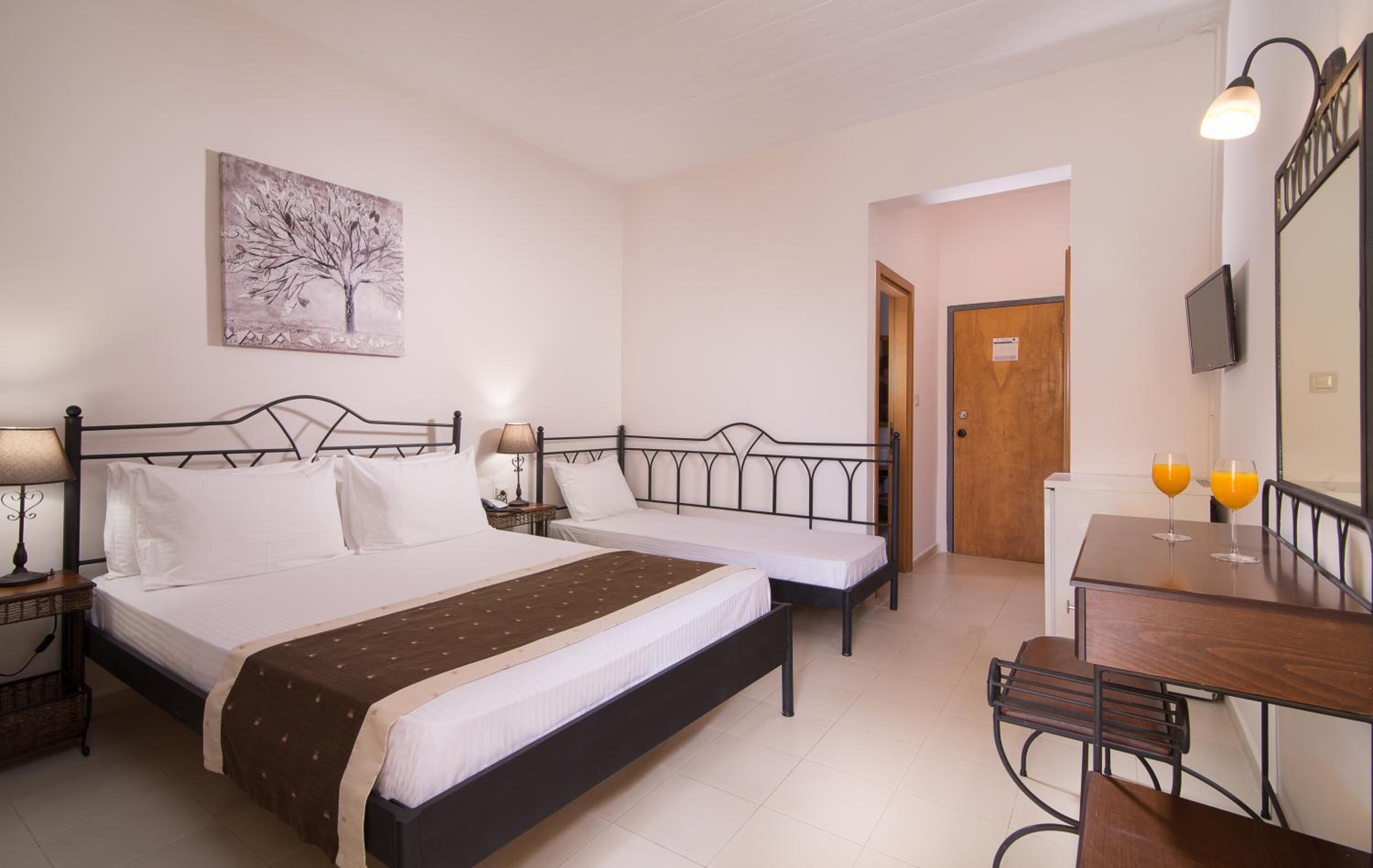 A hotel room with two beds, a desk, a chair, a television, and a painting on the wall.