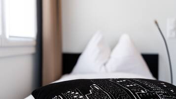 A bed with a black and white patterned pillow and white pillows.