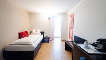 Habitación de hotel moderna con cama, escritorio, silla, cafetera y vistas al exterior.
