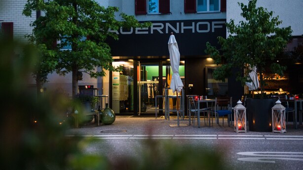 Un restaurant amb terrassa, entrada visible i un rètol amb el nom 'Auerhof'.