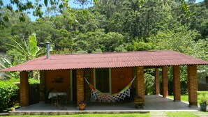 A house with a red tiled roof, brick walls, and a front porch with a hammock. - Chalés Luar da Serra (Santo Antonio do Pinhal)