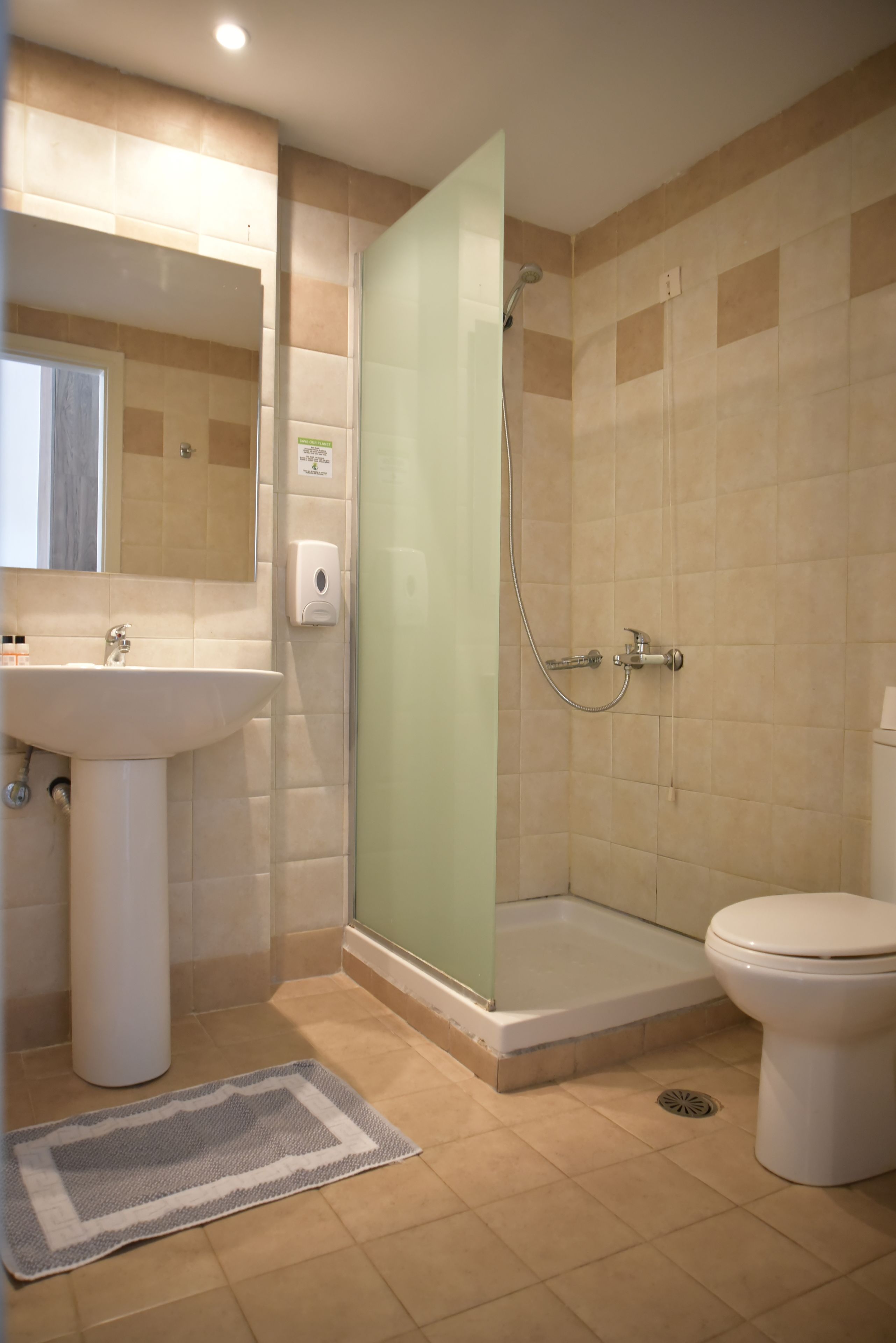 Un baño con ducha, inodoro, lavabo y cabina de ducha con paredes de vidrio.