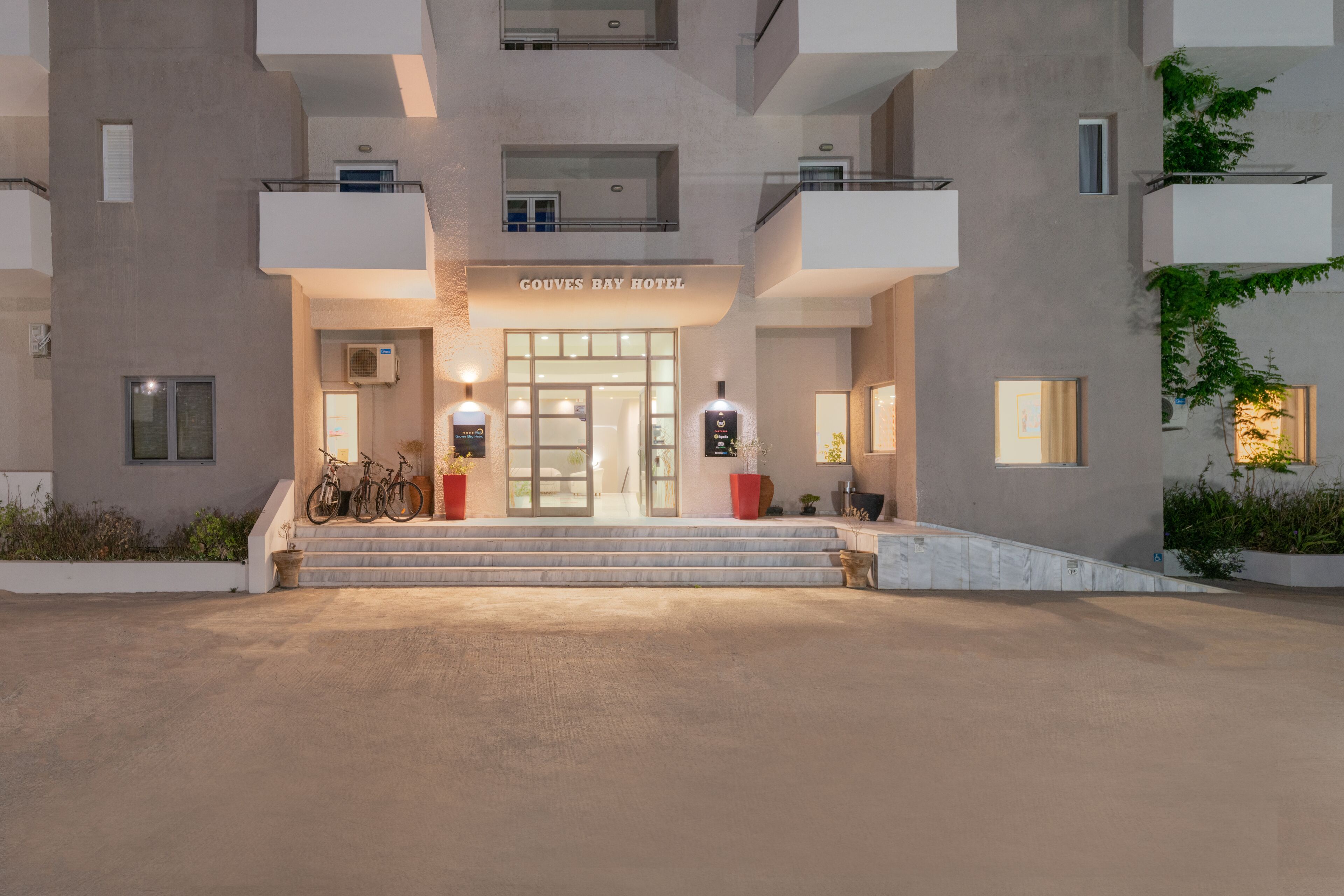 A modern hotel entrance with a flat facade, a central entrance, and a staircase leading up.