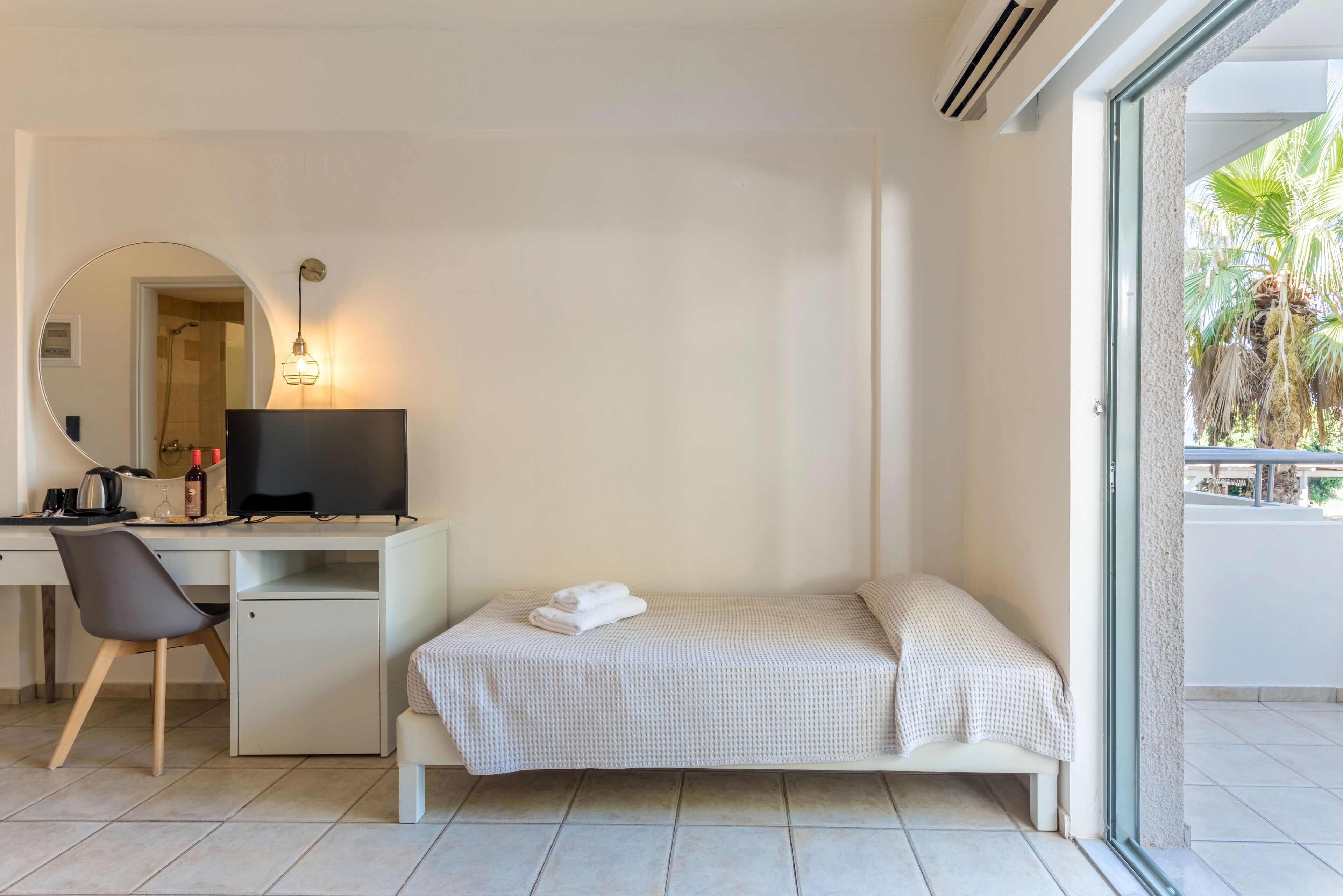 A modern bedroom with a desk, chair, and a bed with a neatly folded towel.