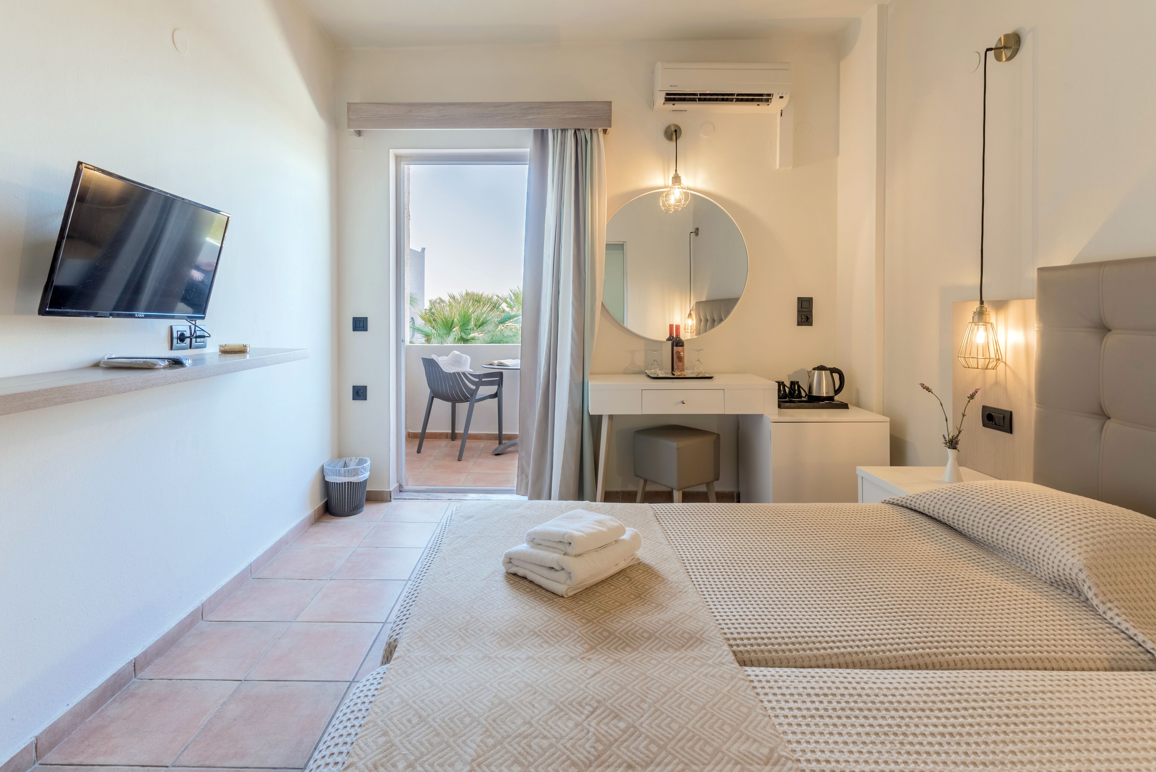 A hotel room with a bed, a TV, a desk, and a bathroom.