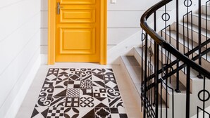 A staircase with a patterned floor leading to a bright yellow door. - Zacisze Apartments by Habitan (Kraków)