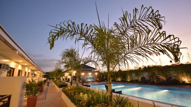 Zona junto a la piscina con piscina, palmeras y un edificio con un cartel que dice "SOUTHWIND".
