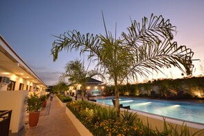 A poolside area with a pool, palm trees, and a building with a sign that reads "SOUTHWIND." - Southwind Palawan (Puerto Princesa)