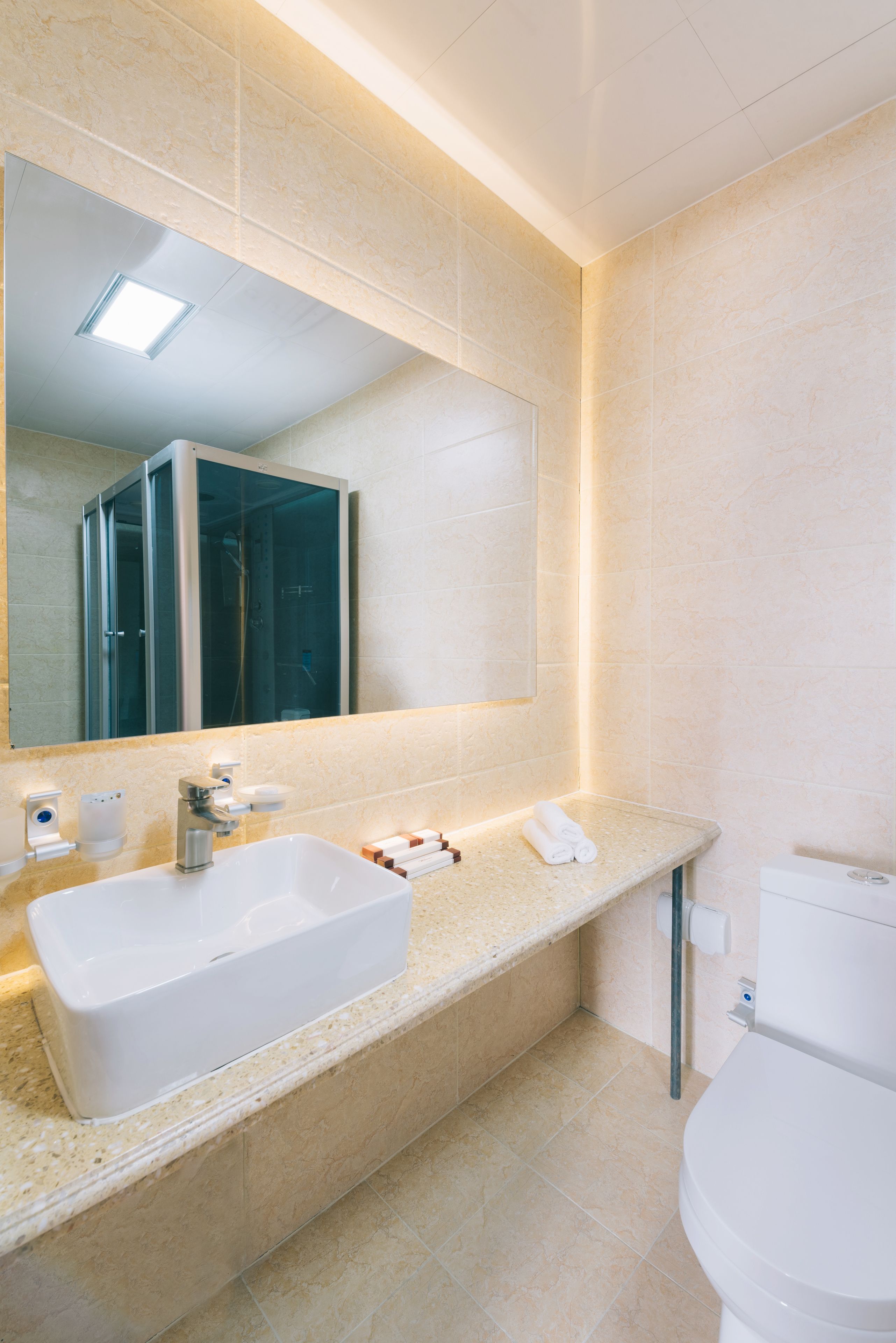 Un bagno moderno con uno specchio grande, un lavandino bianco e un water.