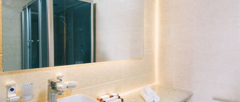 Un bagno moderno con uno specchio grande, un lavandino bianco e un water.