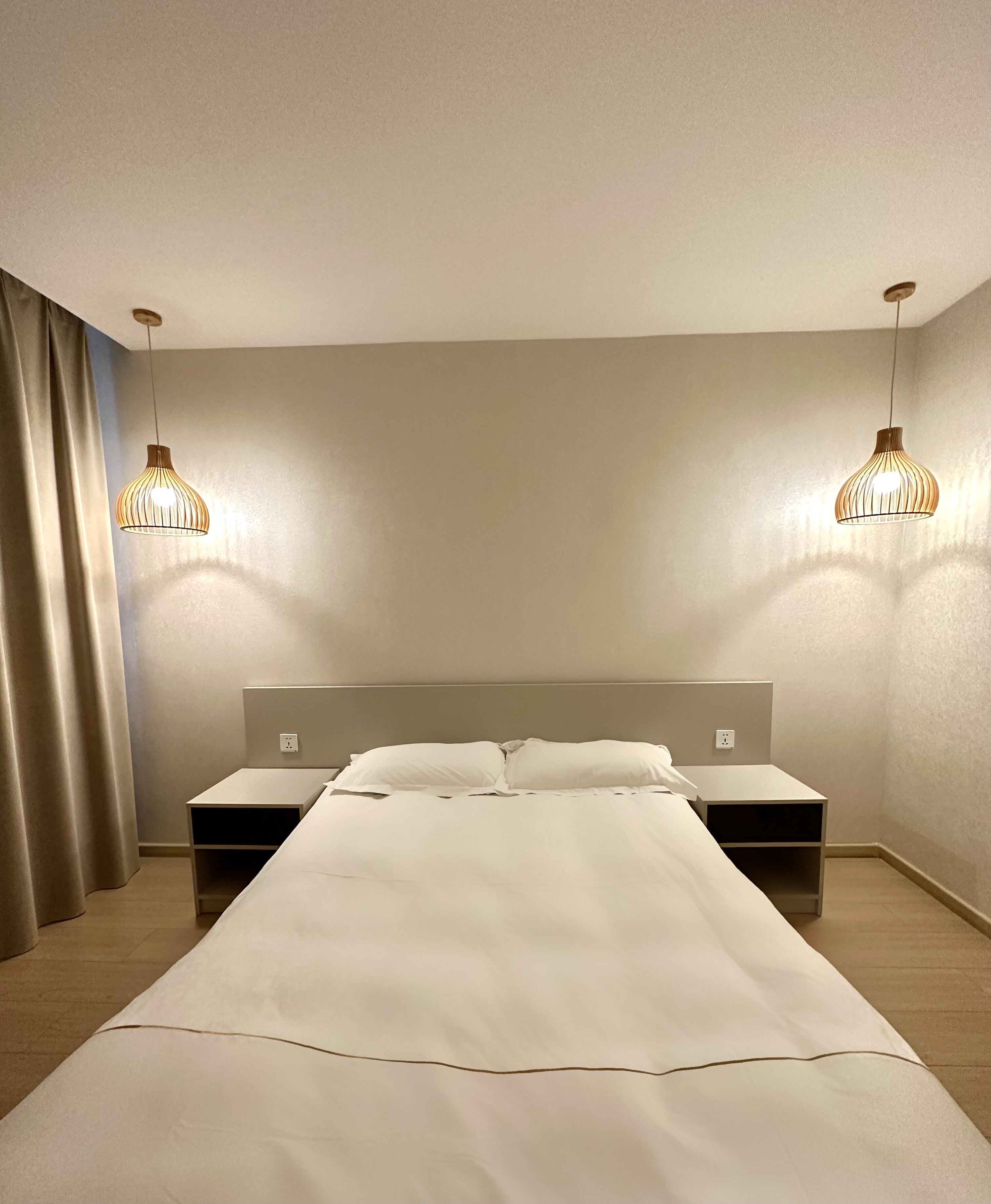 Un dormitorio con una cama grande, dos mesitas de noche y dos lámparas colgantes.